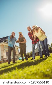 Group Of Senior People Having Fun Playing Mini Golf At The Backyard Lawn On A Sunny Summer Day