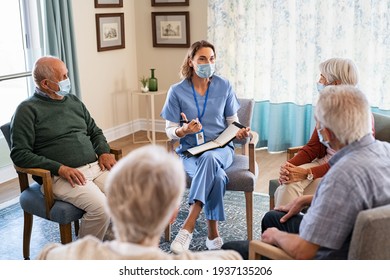 Group of senior people listening to nurse wearing face mask. Counselor wearing surgical mask talking to group of old people. Psychological support for elderly and lonely people in a community centre.