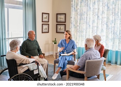 Group Of Senior People Listening To Young Nurse. Psychological Support Group For Elderly And Lonely People In A Community Centre. Group Therapy In Session Sitting In A Circle In A Nursing Home.
