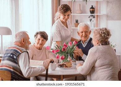 Eine Gruppe von Senioren, die am Tisch in einem Pflegeheim sitzen