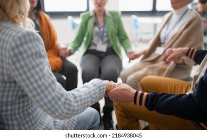 Group Of Senior People Sitting In Circle During Therapy Session, Holding Hands And Praying Together.