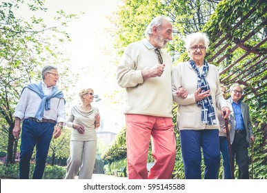 Group Of Senior People With Some Diseases Walking Outdoors - Mature Group Of Friends Spending Time Together