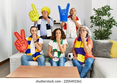 Group Of Senior People Supporting Soccer Team At Home Covering Mouth With Hand, Shocked And Afraid For Mistake. Surprised Expression 