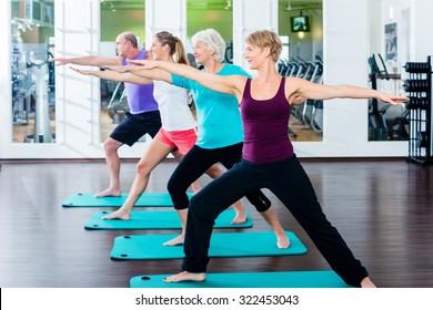 Group Of Senior People And Young Woman And Men In Fitness Gym Doing Gymnastics 