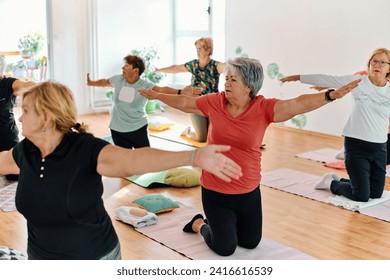 A group of senior women engage in various yoga exercises, including neck, back, and leg stretches, under the guidance of a trainer in a sunlit space, promoting well-being and harmony - Powered by Shutterstock