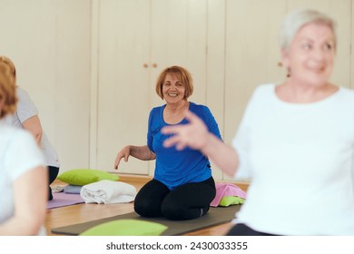 A group of senior women engage in various yoga exercises, including neck, back, and leg stretches, under the guidance of a trainer in a sunlit space, promoting well-being and harmony - Powered by Shutterstock