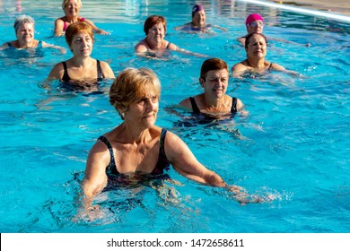 Group Of Senior Women Warming Up In Outdoor Pool. Elderly Ladies About To Do Aqua Gym Class.

