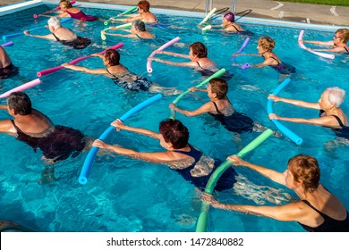 Group of senior women working out with foam noodles. Side view of active ladies in outdoor swimming pool. - Powered by Shutterstock