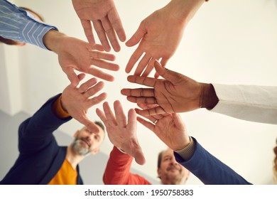 Group Of Senior And Young Multiracial Business People Joining Hands Showing Unity And Solidarity, View From Below, Warm Toned Low Angle Close Up Shot. Concept Of Mutual Help, Teamwork And Team Spirit