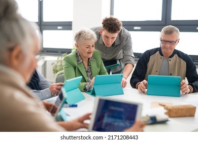 Group Of Seniors Attending IT Class In Community Centre With Teacher