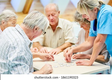 Group of seniors and caregivers with puzzle in retirement home while playing at leisure - Powered by Shutterstock