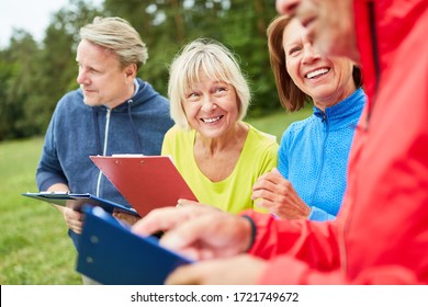 Group Of Seniors With Clipboard During A Scavenger Hunt As A Game On The Ground