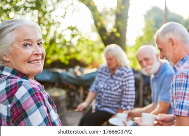 Group Of Seniors In The Garden In Retirement Home Drinking Coffee Together