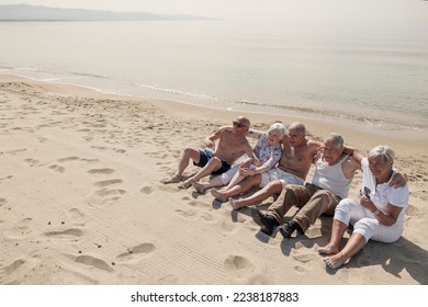 A group of seniors have fun sitting on the beach by the sea - Shutterstock ID 2238187883