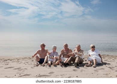 A group of seniors have fun sitting on the beach by the sea - Shutterstock ID 2238187885