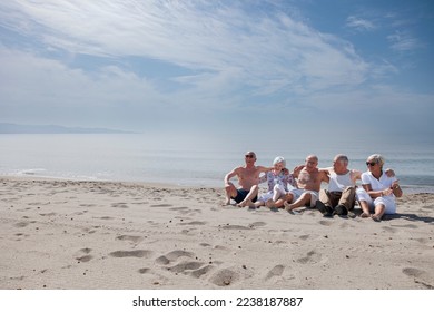 A group of seniors have fun sitting on the beach by the sea - Shutterstock ID 2238187887