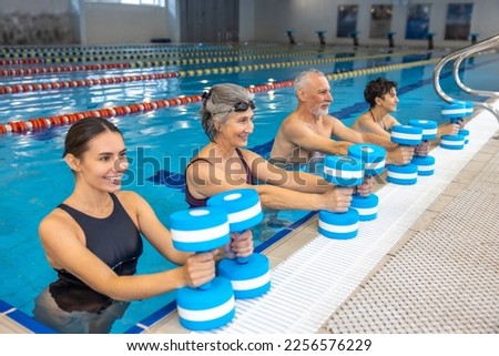 Group of seniors having an exercise with dumbbels during water aerobics class