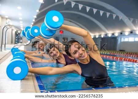 Group of seniors having an exercise with dumbbels during water aerobics class