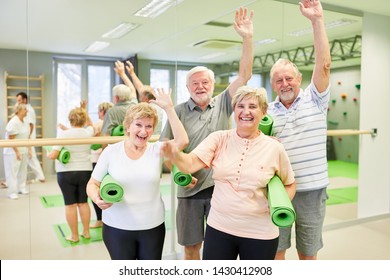 Group of seniors having fun together at the fitness class in the gym and waving to the camera