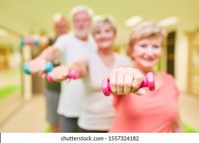 Grupo de personas mayores en rehabilitación de fisioterapia durante el entrenamiento de peso con campanas