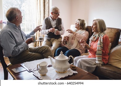 Group of seniors are sitting in the living room of a home together, enjoying a pot of tea and a chit-chat together.  - Powered by Shutterstock