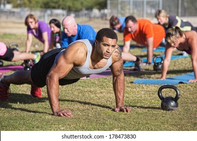 Group of serious adults doing push-ups outdoors - Powered by Shutterstock