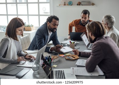 Group Of Serious Businesspeople Having Discussing At Meeting Room.