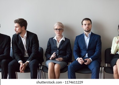 Group Of Serious Young And Middle Aged Candidates Professionals Business People Sitting In Chairs In Queue Waiting Job Interview, For One Position At Company. Human Resources, Hr, Recruitment Concept