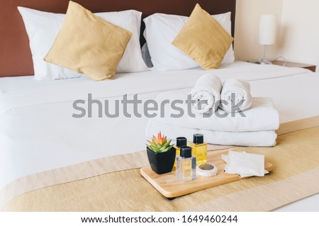 Group set of free hotel amenities (such as towels, shampoo, soap, gel etc) on the bed. Hotel amenities is something of a premium nature provided in addition to the room when renting a room.