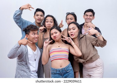 A group of seven happy and close friends in their late teens to early 20s making wacky poses. A fun, modern Gen Z team. Isolated on a white background. - Shutterstock ID 2229039611