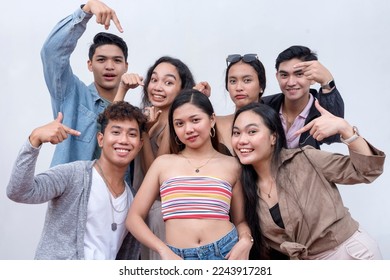 A group of seven happy and young people in their late teens to early 20s pointing to their friend in the middle. Presentation and advertising concept. Isolated on a white backdrop.