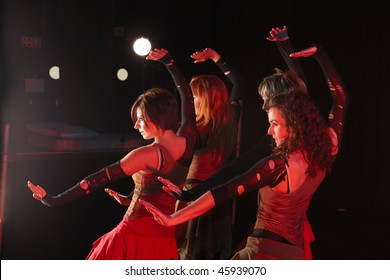 A group of sexy young freestyle dancers on a dark stage with red and blue stage lights