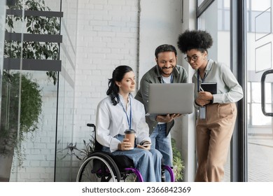 group shot of diverse business people, disabled woman on wheelchair looking at laptop with coworkers