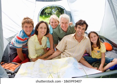 Group Shot Of A Multi Generational Family Inside A Tent On A Camping Trip Smiles At The Camera.