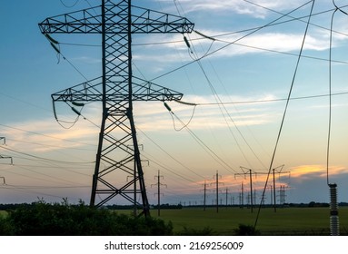 Group silhouette of power transmission towers against the backdrop of sunset. High voltage texture pole, overhead power lines, industrial background. panoramic style