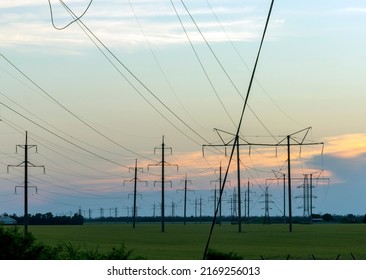 Group silhouette of power transmission towers against the backdrop of sunset. High voltage texture pole, overhead power lines, industrial background. panoramic style
