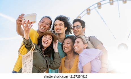 Group Of Six People Having Fun Taking Photos With Vintage Camera, Influeancers Of Generation Z Creating Contents For Social Media, Farris Wheel On Background