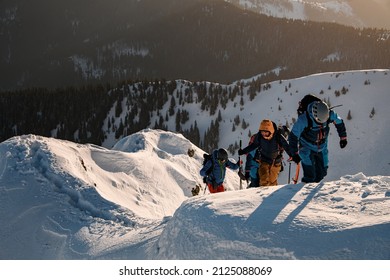 Group Of Skiers In Bright Ski Suits Are Climbing Up At Snow-covered Mountain Trail. Ski Touring And Freeride Concept