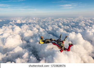 Group Of Skydivers Above The Clouds.