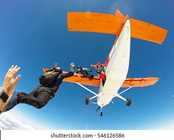 A Group Of Skydivers Friends Jumping From The Orange Plane