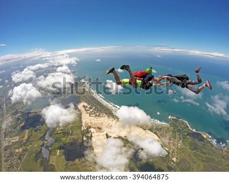 A group of skydiving friends having fun in the skies. Soft focus in background. Ibiraquera Brazil.