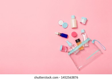 Group of small bottles for travelling on pinkbackground. Copy space for your ideas. Flat lay composition of cosmetic products. Top view of cream containers with cotton pads.