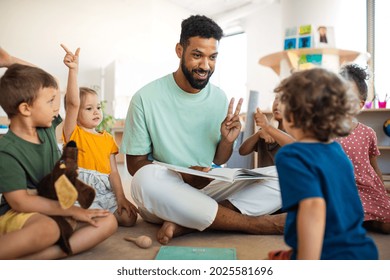 Group of small nursery school children with man teacher sitting on floor indoors in classroom, having lesson. - Shutterstock ID 2025581696