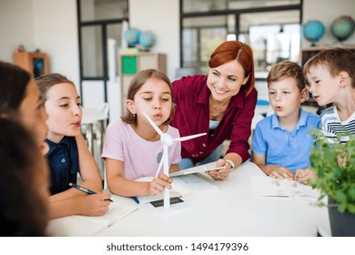 A Group Of Small School Kids With Teacher In Class Learning About Environment.