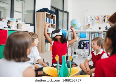 A Group Of Small School Kids With VR Goggles Sitting On The Floor In Class.