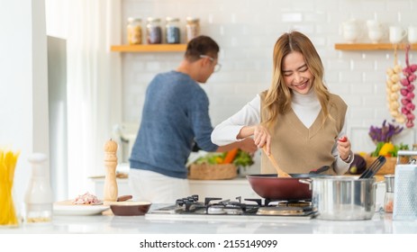 Group Of Smiling Asian People Friends Enjoy Cooking With Talking Together In The Kitchen At Home. Happy Man And Woman Having Dinner Party Meeting Celebration Eating Food Together On Holiday Vacation