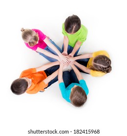 Group of smiling children sitting on the floor in a circle holding hands - isolated on white.
