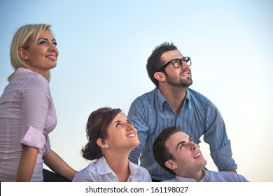 Group Of Smiling Corporate People Sitting Outside Looking Up