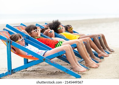 Group Of Smiling Diversity Little Child Boy And Girl In Swimwear Lying On Beach Chair Together On Tropical Beach On Summer Vacation. Happy Children Kid Enjoy And Fun Outdoor Lifestyle On Beach Holiday