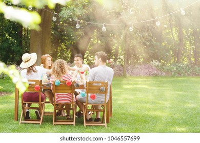 Group of smiling friends eating lunch at  a garden party
